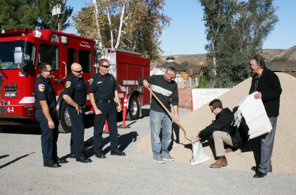 GOT SANDBAGS: Pictured are Public Safety Chairman Rob Mucha shoveling gravel into a bag held by Eric Werner, president of Werner Corp., as Robert Lizano, general manager of Tom's Farms looks on. Station 64 firefighters, pictured from left, are firefighter/paramedic Brandon Forsberg, Engineer Kevin Hansen and Capt. Lorne Ellickson. Thank you to all for providing this community service.